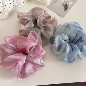 Detail of three gradient organza scrunchies in pink, blue, and gray with pearly luster finish