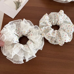 Detailed macro view of floral fabric scrunchies with white lace edges on wood