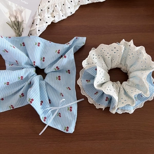 Detail of blue plaid cherry hair scrunchies with white lace and ribbon bow on wood