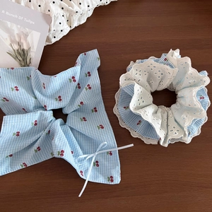 Detail of blue plaid cherry bow scrunchie and vintage lace hair tie set on wooden desk