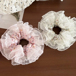 Detail of floral scrunchies with lace trim and cotton fabric on a wooden table