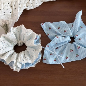 Close-up of sweet blue plaid scrunchie with cherry pattern and lace trim details