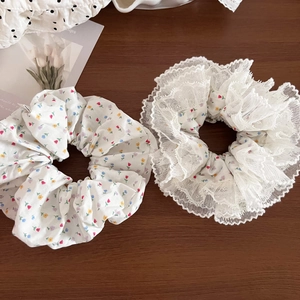 Detail of floral scrunchies with white lace edges on a warm wooden background