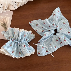 Detail view of light blue checkered scrunchie with cherry print and white lace edges
