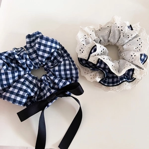 Detailed close-up of navy plaid scrunchie with lace trim and black satin ribbon bow