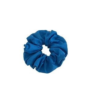 Chouchou en coton bleu vif minimaliste avec texture naturelle sur fond blanc pur