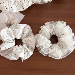 Detailed view of floral pattern scrunchies with white lace edges on wooden background