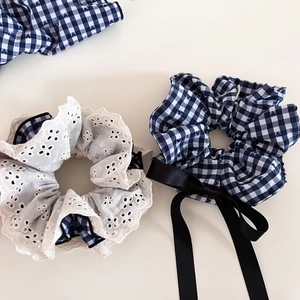 Detail view of navy plaid scrunchies with black satin ribbons and delicate white floral lace