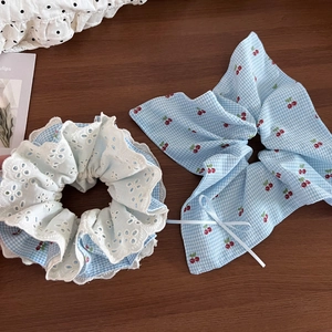 Detail of blue plaid cherry hair scrunchie set with lace trim and bow on wooden background