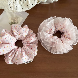 Pink floral scrunchies with white lace trim set on a rustic wooden background