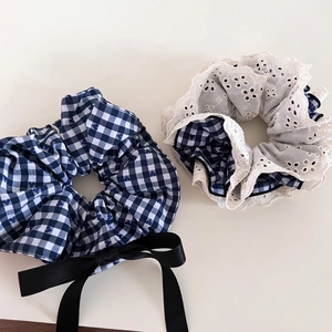 Detailed view of navy blue plaid scrunchie with lace trim and elegant black ribbon bow tie