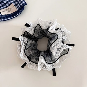Detail of multi-layered white lace and polka dot mesh scrunchie with black ribbon