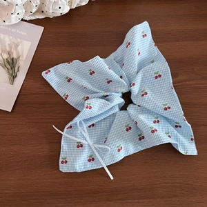 Detail of blue gingham scrunchie with cherry print and decorative white ribbon bow