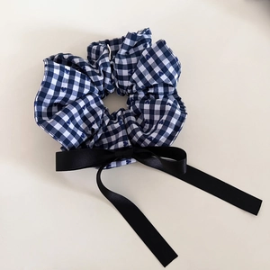 Detailed close-up of navy blue plaid scrunchie with long black satin ribbon bow