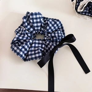 Detail of navy plaid hair scrunchie with lace edge and elegant black ribbon bow