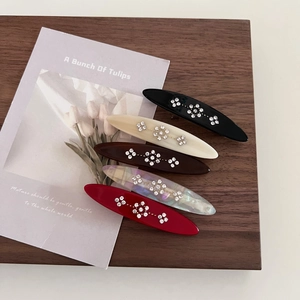 Five-piece vintage floral acetate hair clips set with sparkling rhinestones on wood