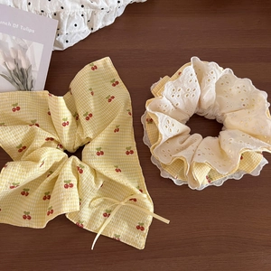 Detail showing yellow plaid cherry hair scrunchies with white lace and ribbon bow