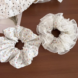 Floral print hair scrunchies with white lace trim on a rustic wooden background