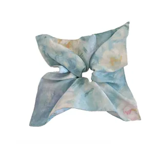 Detail of artistic watercolor floral bow scrunchie in premium satin with blue and yellow hues