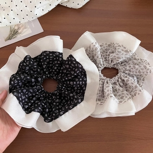 Close-up of double-layer chiffon scrunchies with floral and paisley patterns on wood surface