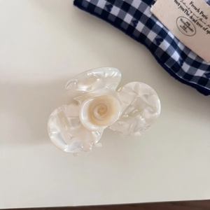 Detail of white acetate orchid hair claw with elegant pearlescent marble texture