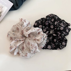 Detail of two floral chiffon scrunchies in cream and black with pink flower patterns