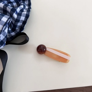 Detail of vintage amber acetate hair clip with brown bead accents and pink stripe inlay
