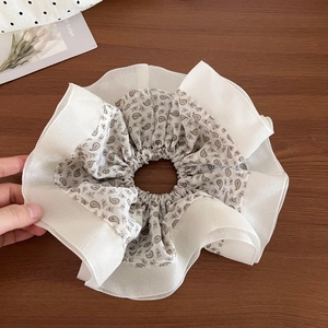 Detail of oversized paisley chiffon hair scrunchie with layered pleated white trim