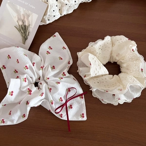 Sweet cherry print bow scrunchie and cream lace hair tie set on a wooden table