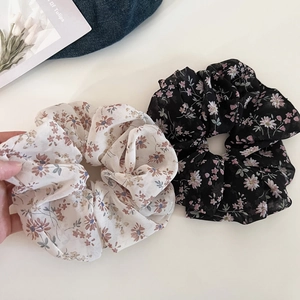 Floral print chiffon scrunchies in cream and black displayed with a denim background