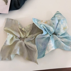 Detail view of two watercolor floral organza scrunchies in blue and green tones