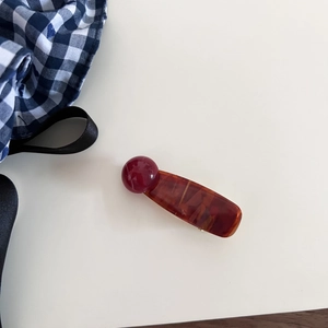 Close-up of a retro amber resin hair clip with a red bead accent on white background