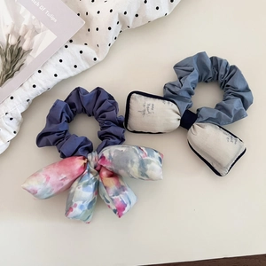 Close-up of fabric floral bow hair ties with ink painting patterns on polka dot background