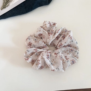 Detail shot of vintage floral chiffon scrunchie with delicate patterns on white surface