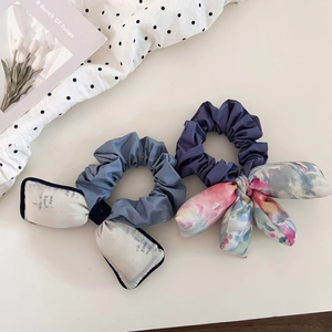 Detail view of two sweet watercolor floral bow scrunchies in blue and purple tones
