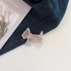 Vue détaillée d'une pince à cheveux chiot irisée avec strass sur un fond de jean bleu