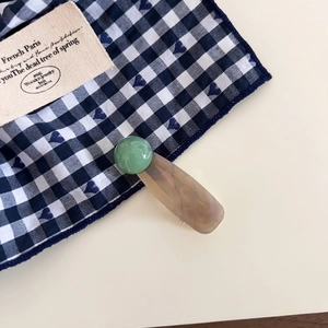 Detail of emerald green dome and marble pattern acetate duckbill hair clip on fabric