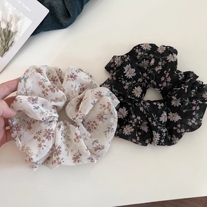 Detail view of two chiffon floral scrunchies in white and black with soft petal prints