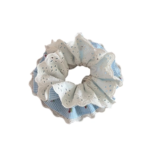 Blue plaid scrunchie with cherry print and white floral eyelet lace embroidery on plain background