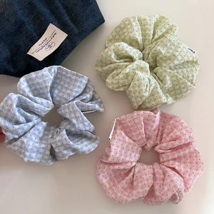 Detailed close-up of a three-piece set of pastel plaid and polka dot hair scrunchies