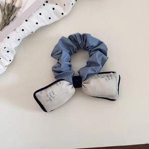 Blue aesthetic scrunchie with beige patterned bow for elegant bun hair styling