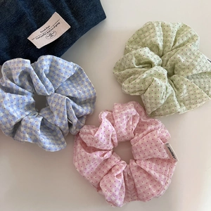 Detailed view of candy-colored plaid scrunchies with red polka dots and micro brand labels