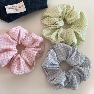 Close-up of three checkered and polka dot hair scrunchies in pastel pink, blue, and green