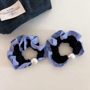 Detail of two vintage blue striped scrunchies with elegant white pearls on a clean background