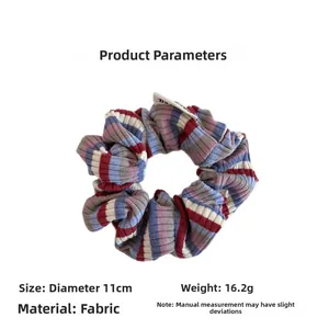 Macro detail of a colorful striped knitted scrunchie showing ribbed texture and brand label