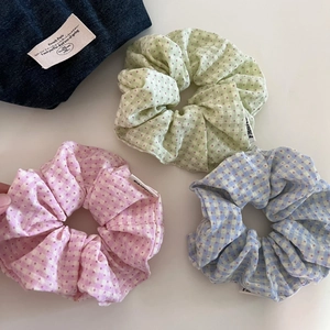 Close-up of pastel gingham scrunchies in light green, pink, and blue cotton fabric