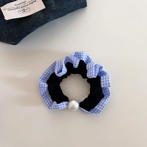 Detail of blue gingham scrunchie with ruffle edge and large white faux pearl accent