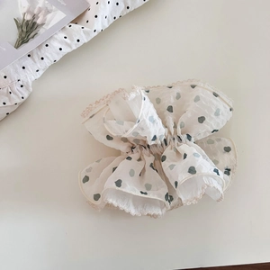 Detail of white organza scrunchie with green heart prints and delicate lace edging