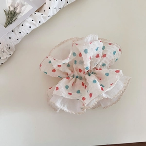 Close-up of sweet chiffon hair scrunchie with colorful heart patterns and lace edges