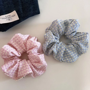 Close-up of pink and blue plaid polka dot scrunchies on a neutral background